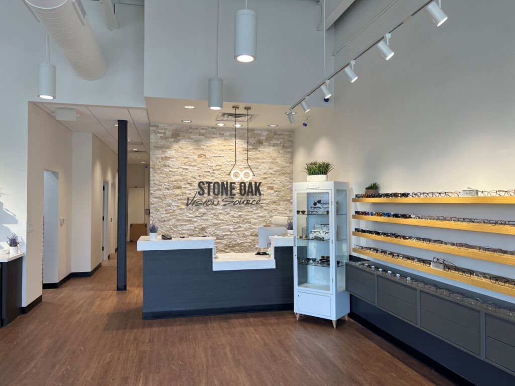 A modern and brightly-lit eyewear store constructed by D Barnes Construction, with an array of glasses on display, a decorative stone accent wall, and a welcoming reception desk.